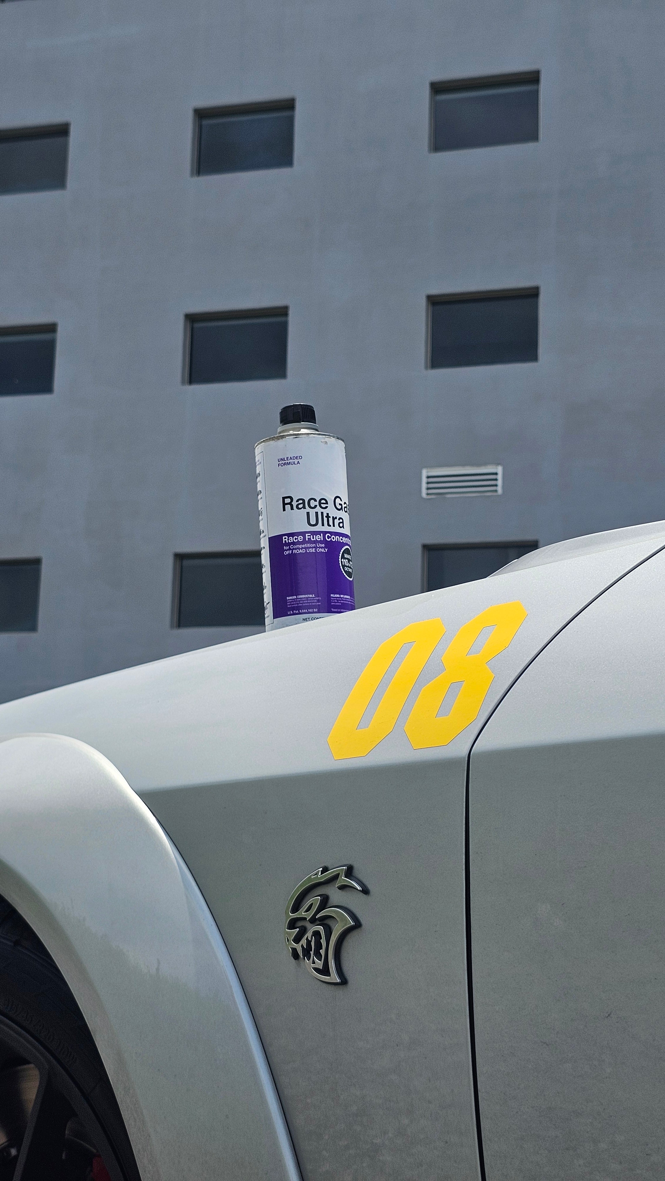 Lata de Race Gas Ultra en el cofre de un Hellcat de carreras, destacando el emblema del Hellcat y el número 08